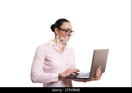 Portrait latéral d'une jeune femme d'affaires belle, gestionnaire tapant du texte sur un ordinateur portable. Arrière-plan blanc, espace de copie pour la promotion Banque D'Images