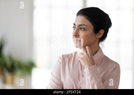 Jeune femme indienne pensive regarde dans la pensée à distance Banque D'Images