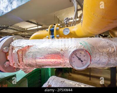 Vue rapprochée du thermomètre industriel sur le tuyau du système d'isolation en feuille d'argent. Banque D'Images