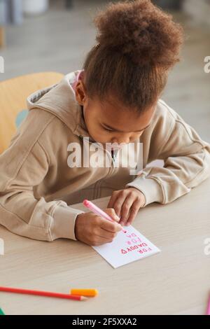 Portrait vertical d'une jolie fille afro-américaine faisant une carte faite à la main comme cadeau pour la fête des Pères, espace de copie Banque D'Images