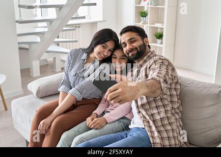 Une famille indienne heureuse avec une fille adolescente qui s'amuse prend le selfie au téléphone à la maison. Banque D'Images