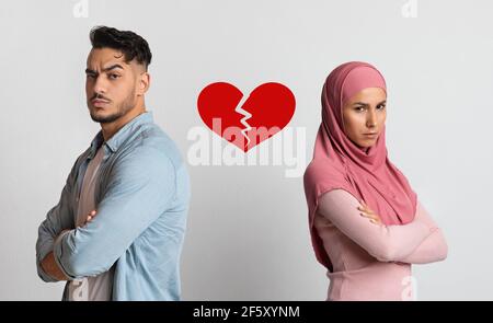 Concept de rupture et de divorce. Collage de couple noir malheureux debout dos à dos avec le symbole de coeur déchiré entre eux sur fond clair Banque D'Images