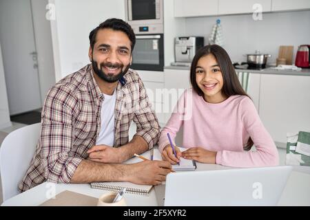 Joyeux jeune père indien aidant la fille de l'adolescence à apprendre à la maison, portrait. Banque D'Images