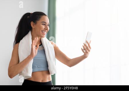 Femme sportive avec serviette de bain sur smartphone Banque D'Images