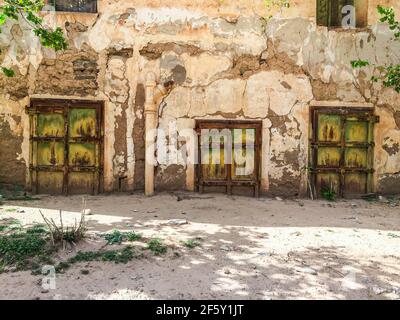 Aouli, Maroc - 10 avril 2015. Portes rouillées vertes de maison abandonnée, partiellement enterrées de sable Banque D'Images