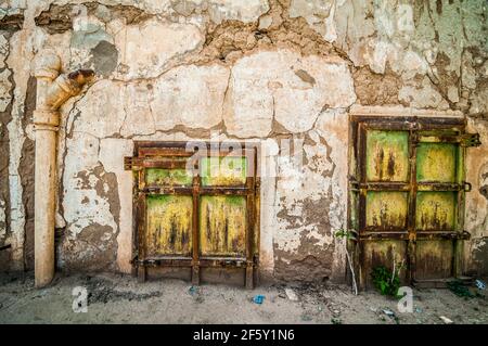 Aouli, Maroc - 10 avril 2015. Portes rouillées vertes de maison abandonnée, partiellement enterrées de sable Banque D'Images