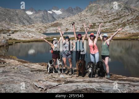 Des amies insouciantes avec des chiens debout à Titcomb Basin pendant vacances Banque D'Images