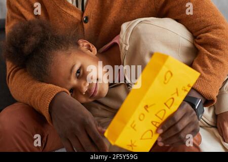 Portrait d'une adorable fille afro-américaine en cuddling avec un père tenant main Cadeau pour la fête des Pères Banque D'Images