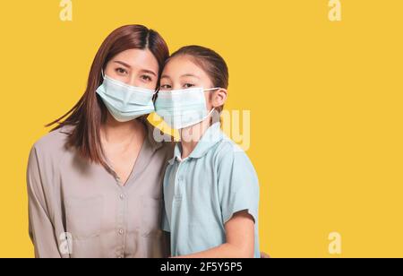 La mère embrasse la petite fille dans des masques médicaux de protection pendant Covid-19 pandémies Banque D'Images