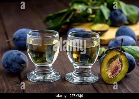 Brandy aux prunes ou schnaps dans des verres et prunes fraîches et savoureuses sur une table en bois. Mise au point sélective. Banque D'Images