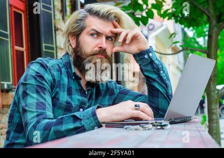 Homme barbu sérieux travaillant sur un ordinateur portable. Travail en ligne. Freelance. Banque D'Images