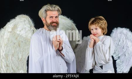 Père et fils en costumes d'ange. Saint-Valentin. Famille heureuse avec ailes blanches. Banque D'Images