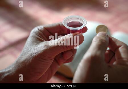 Homme tenant du pain et du vin dans la communion ou l'Eucharistie de Hoy. La Sainte bible sur la table à l'arrière-plan. Banque D'Images