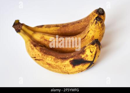 Trois bananes surmûres en taches brunes sur fond blanc. Banque D'Images