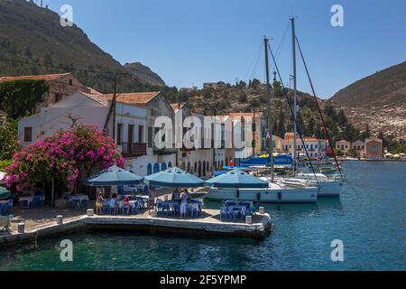 Les touristes s'assoient dans un restaurant sur le port de l'île Kastellorizo (Meis) en Grèce. L'île est située à 2 kilomètres de la Turquie. Banque D'Images