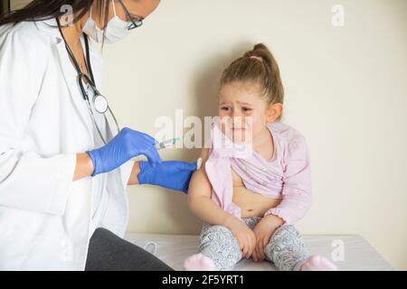 chubby petite fille en examen pédiatrique par son médecin. vacciné par son médecin. Focus sélectif. Vaccin covid bébé Banque D'Images