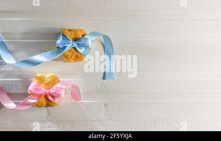 Deux piles de biscuits sous forme de fleurs, reliées par des rubans rose satiné et bleu clair, sur les noeuds. Sur un comptoir blanc mat. Vue de dessus. Banque D'Images