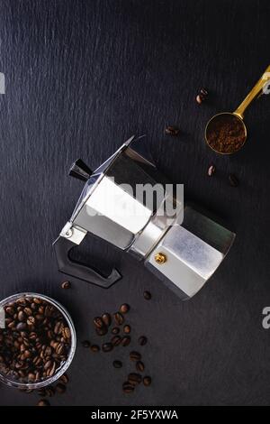 Encore plus de vie avec une marmite de moka et des grains de café sur le noir arrière-plan en pierre Banque D'Images