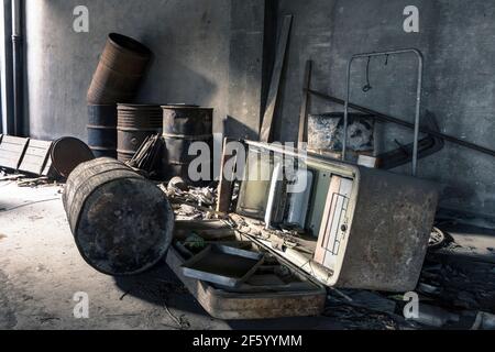 Ancien réfrigérateur et barils rouillés laissés dans une usine déserte, un endroit abandonné Banque D'Images