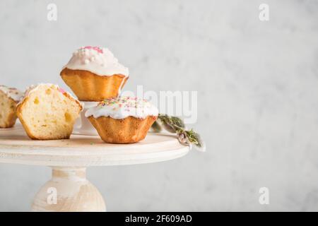 Quelques muffins avec glaçage au chocolat et confiture sur un support en bois blanc sur un fond clair. Vue latérale avec un espace de copie pour le texte. Dessert festif. Banque D'Images