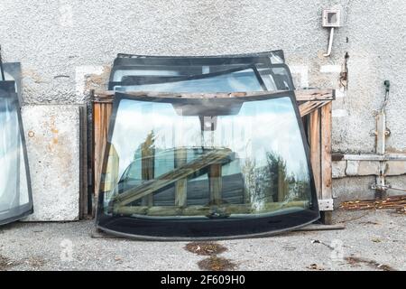 Service de remplacement et de réparation des vitres automatiques. Les vitres de voiture fissurées des voitures se tiennent contre le mur. Banque D'Images