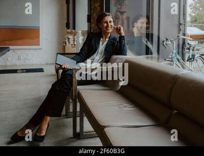 Portrait of smiling businesswoman sitting on sofa at office Banque D'Images