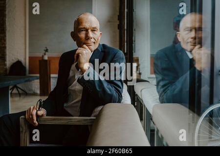 Portrait d'homme d'affaires avec main sur le menton assis au-dessus du canapé au bureau Banque D'Images