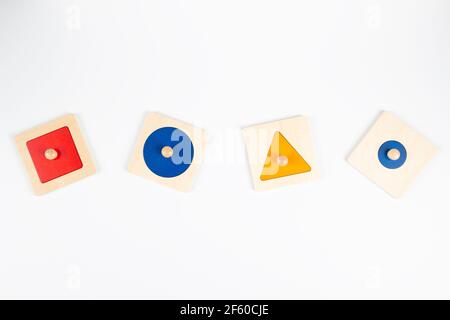 Matériel sensoriel en bois Montessori apprenant des jouets éducatifs sur fond blanc. Jouets de plateau de tri de forme géométrique Banque D'Images