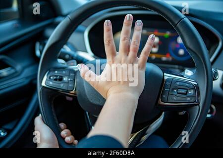 la main féminine appuie sur l'avertisseur sonore sur le volant d'une voiture moderne. pas de visage Banque D'Images