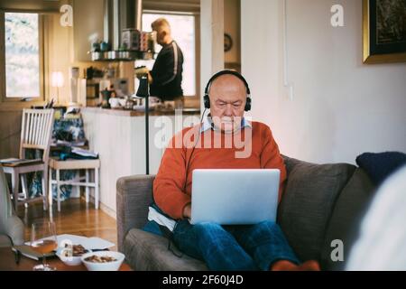 Homme gay senior utilisant un ordinateur portable tout en étant assis à la maison Banque D'Images