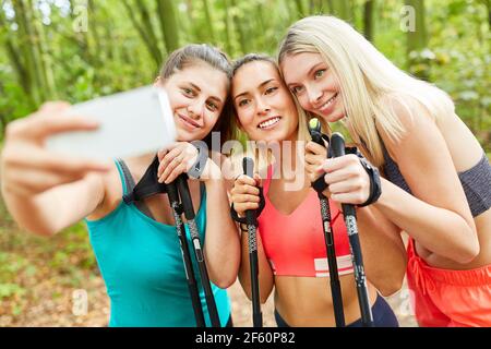 Trois jeunes femmes comme amis prennent un selfie pendant Nordic marche Banque D'Images