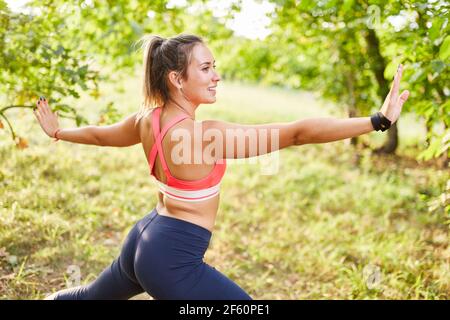 Jeune femme faisant de la gymnastique de forme physique saine ou le tai chi dedans nature en été Banque D'Images