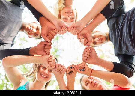 Groupe d'adolescents debout dans un cercle avec des poings serrés pour le renforcement de l'équipe et la motivation Banque D'Images