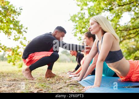 Un entraîneur de yoga enseigne aux jeunes dans un cours de bien-être à nature en été Banque D'Images