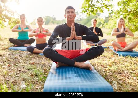 Groupe d'amis ayant une méditation de yoga dans le lotus situation dans la nature en été Banque D'Images