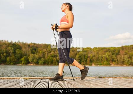 Jeune femme sportive faisant marche nordique pour la forme physique et l'endurance dans la nature Banque D'Images