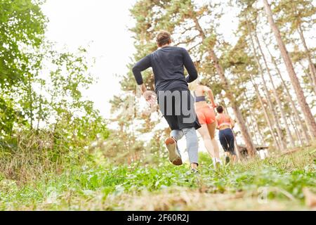 Groupe d'amis faisant courir à travers le pays dans la nature dans le la forêt comme entraînement d'endurance Banque D'Images