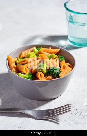 Des pâtes de lentilles rouges au brocoli dans un bol gris. Des pâtes végétaliennes saines avec des légumes. Banque D'Images