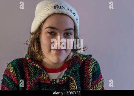 Teeenage fille regardant l'appareil photo portant un bonnet blanc avec un petit sourire. Banque D'Images