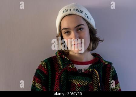 Teeenage fille regardant l'appareil photo portant un bonnet blanc avec un petit sourire. Banque D'Images