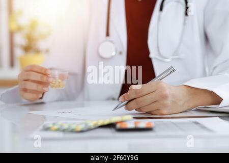 Femme-médecin inconnu remplit la forme de prescription dans la salle ensoleillée, gros plan Banque D'Images