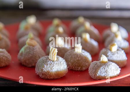 Sucreries au lait faites maison appelées beijinho servies sur un plateau rouge. Sucreries pour la fête d'anniversaire. Desserts délicieux. Des baisers décorés et servis sur une pl colorée Banque D'Images