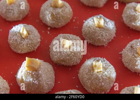 Sucreries au lait faites maison appelées beijinho servies sur un plateau rouge. Sucreries pour la fête d'anniversaire. Desserts délicieux. Des baisers décorés et servis sur une pl colorée Banque D'Images