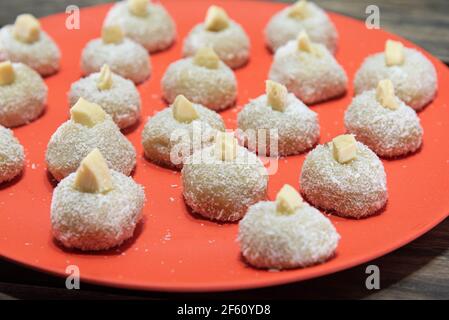 Sucreries au lait faites maison appelées beijinho servies sur un plateau rouge. Sucreries pour la fête d'anniversaire. Desserts délicieux. Des baisers décorés et servis sur une pl colorée Banque D'Images