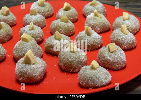 Sucreries au lait faites maison appelées beijinho servies sur un plateau rouge. Sucreries pour la fête d'anniversaire. Desserts délicieux. Des baisers décorés et servis sur une pl colorée Banque D'Images