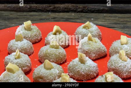 Sucreries au lait faites maison appelées beijinho servies sur un plateau rouge. Sucreries pour la fête d'anniversaire. Desserts délicieux. Des baisers décorés et servis sur une pl colorée Banque D'Images