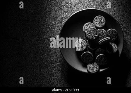 KRASNOYARSK, RUSSIE, 9 février 2020 : biscuits oreiro noirs en gros plan dans une assiette, vue du dessus. Arrière-plan texturé sombre. Banque D'Images