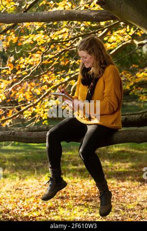 Femme esquissant, assise sur une branche d'arbre Banque D'Images