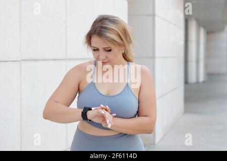Femme de taille plus jolie qui vérifie son activité et s'ammount de calories brûlées via l'application sur le smartphone Banque D'Images