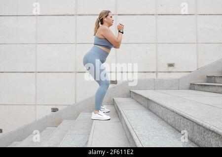Vue latérale de la taille plus jeune femme sautant vers le haut les escaliers pour brancher ses jambes et colles Banque D'Images